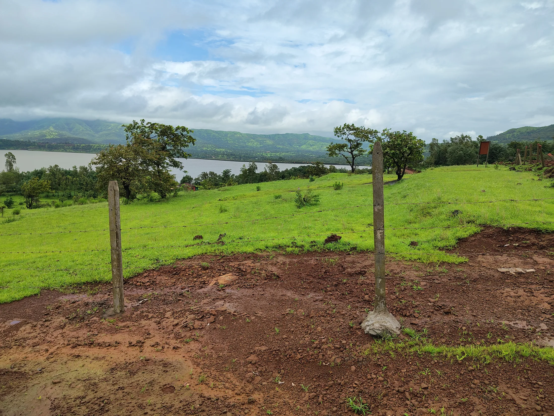 Grassy site with hills and the dam beyond